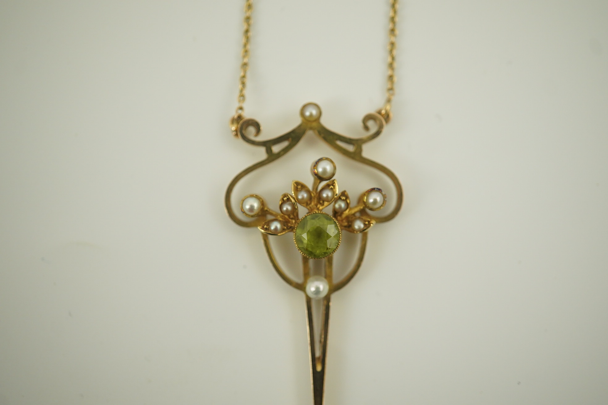 An early 20th century style gold, peridot and seed pearl set drop pendant, on an 18k gold chain